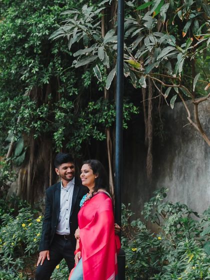 A couple sharing a smile in a beautiful garden setting. We use natural elements like trees and foliage to frame our subjects beautifully.