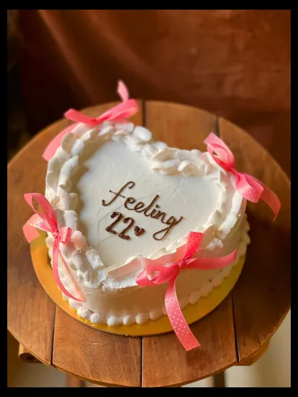 "Feeling 22" and celebrating in style with this heart-shaped cake. The pink ribbon bows add a playful and feminine touch.