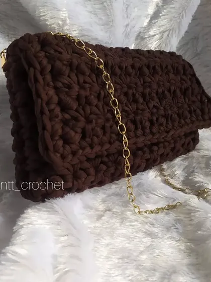For a more structured and elegant look, I use chunky T-shirt yarn. This brown clutch has a sturdy feel and is paired with a gold chain strap, making it perfect for evenings out.