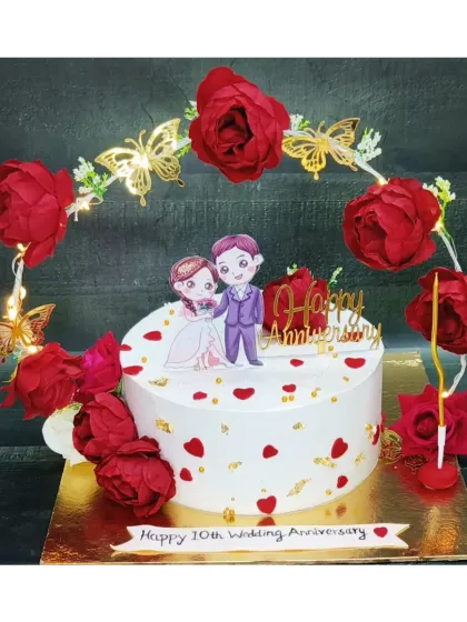 A 10th wedding anniversary cake surrounded by a beautiful arch of red flowers and butterflies. This is a fresh whipped cream chocolate cake, designed to be a showstopper.