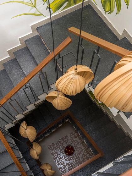 A bird's-eye view of the Mathrukrupa staircase, highlighting the contrast between the dark granite steps, the patterned tile risers, and the sculptural wooden pendant lights.