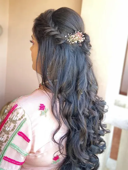 A simple braided half-up style with soft waves. The small floral clip adds a delicate and pretty detail.