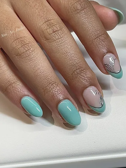 A modern and chic design with mint green nails and an abstract silver flower accent.
