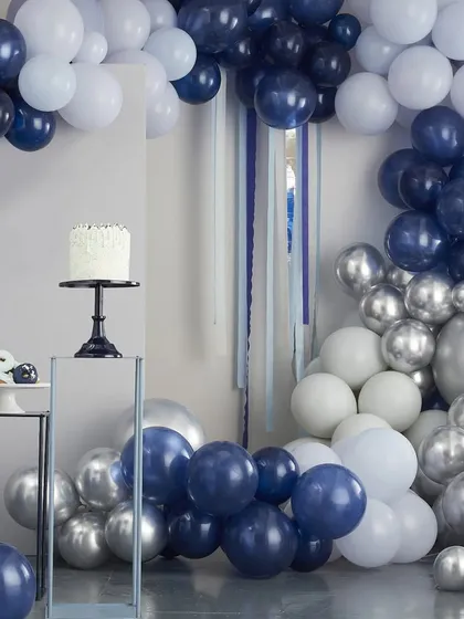 A modern and chic balloon arch in shades of navy blue, light blue, white, and metallic silver. This setup is perfect for a stylish baby shower or birthday party, shown here with cake stands ready for dessert.