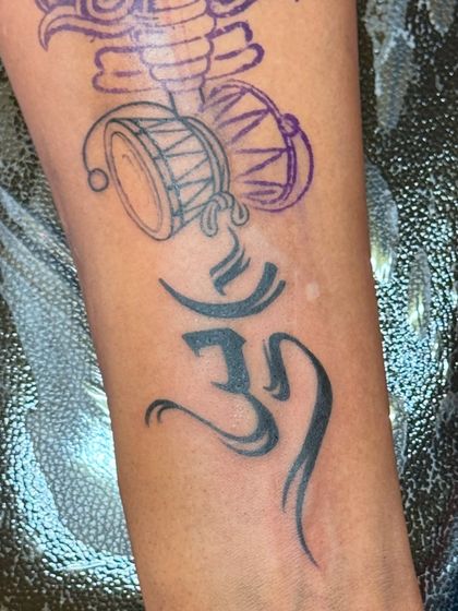 A close-up of the Om symbol being tattooed during the spiritual forearm piece session.
