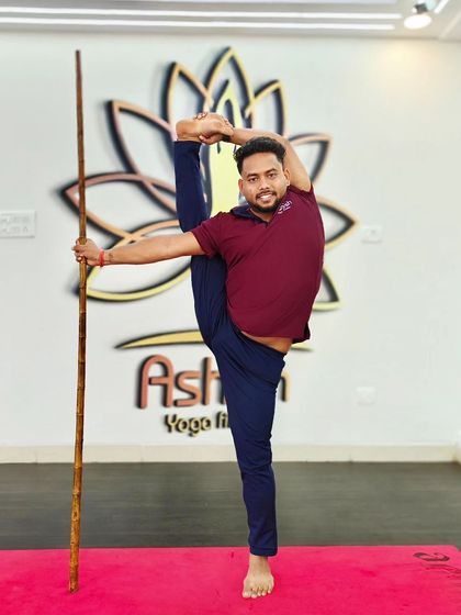 Stick yoga is excellent for improving balance and flexibility. Here, a student uses a stick to assist with a standing split variation.