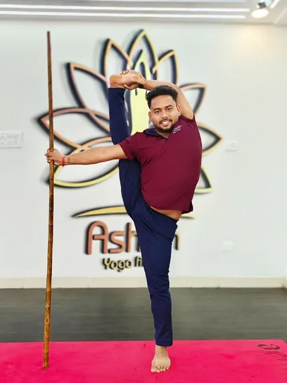 A student uses a bamboo stick for balance while practicing an impressive standing split. This prop helps to steady the body while focusing on the stretch.