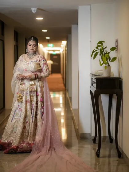 A full-length bridal portrait in a quiet hallway. This shot showcases the entire ensemble, from the detailed lehenga to the long, flowing veil, creating a sense of anticipation.