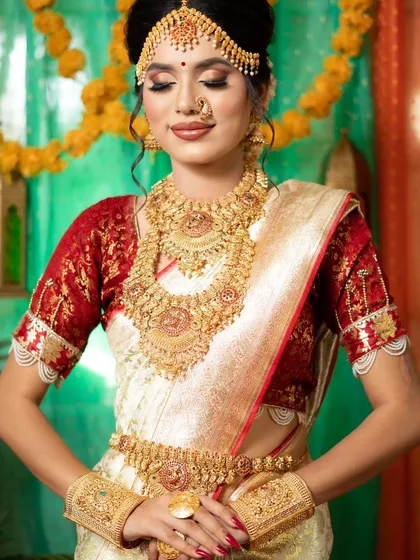 This is my classic South Indian temple jewellery set, featuring intricate gold work with goddess motifs. The set includes a choker, a long haram necklace, jhumkas, a maang tikka, and a kamarbandh, perfect for a traditional bridal look.