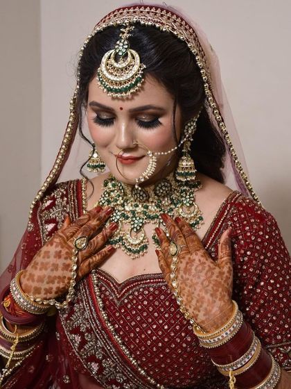 This bride is admiring the stunning green and white Kundan necklace she rented to pair with her maroon lehenga. We help you find the perfect accessories for your outfit.