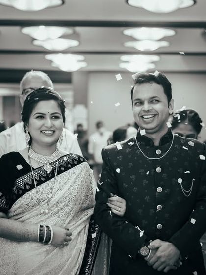 A joyful black and white photo of the couple's entrance at their engagement ceremony, showered with confetti. This captures the celebratory and happy atmosphere of the event.