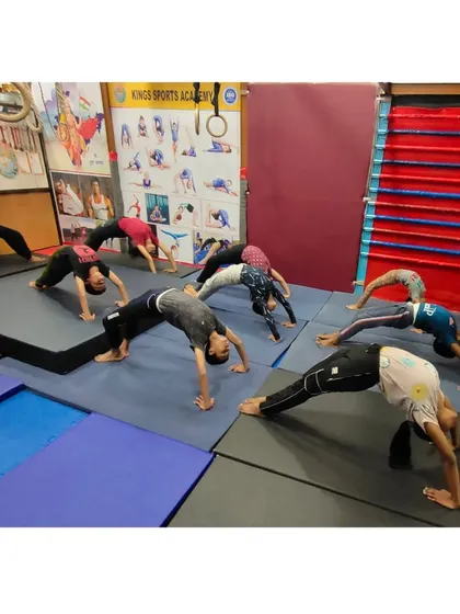 A look inside our group classes where students work on flexibility and back strength. Here, a group practices Chakrasana, or the wheel pose, on padded mats, showing the focused and disciplined environment of our academy.