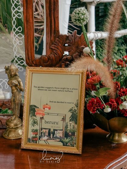 A close-up of the entrance decor, featuring Kerala saree drapes, temple bells, and teak furniture, celebrating tradition and craftsmanship.