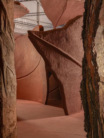 A close-up view between the sculptural forms of the 'Terra' installation. The texture and form of the giant leaves create an enveloping, comforting space that speaks to the feeling of coming home and finding a sense of completeness.