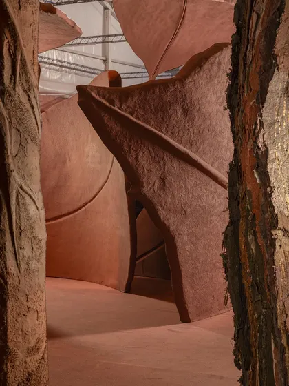 Peeking through the monumental forms of the 'Terra' installation. The layered structures create intimate, cave-like spaces that invite exploration and evoke a sense of sanctuary and completeness.