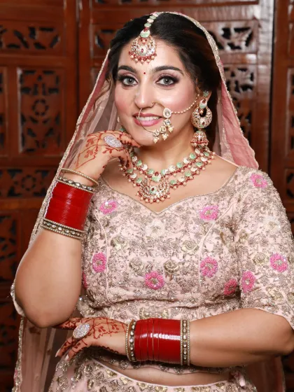 A beautiful bride in a pastel peach lehenga. The makeup is soft and glowing, with a focus on a flawless complexion and a happy smile.