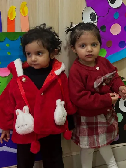 Two little friends in their festive red outfits pose for a photo during a birthday celebration.