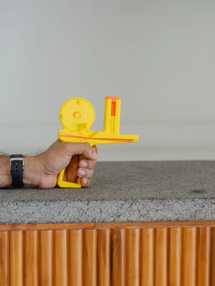 A hand holding the completed disc launcher, ready to fire.