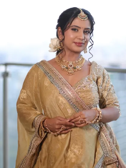 A full view of a timeless bridal look in golden hues. This showcases not just the makeup, but also the complete styling with hair and lehenga draping to create an elegant and cohesive appearance.