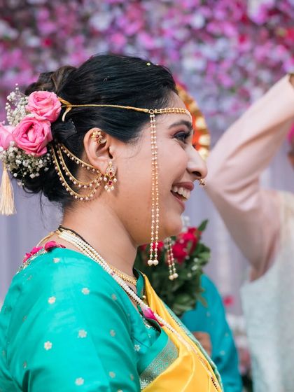 A side profile of a happy bride, adorned with traditional Maharashtrian jewelry.