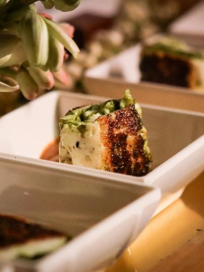 A seared paneer appetizer with a green chutney crust. This bite-sized dish is packed with flavour and showcases our ability to create elegant, modern Indian appetizers.