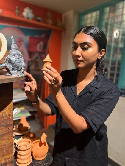 A guest examines different unpainted and finished pieces, getting ideas for her own ceramic painting project.