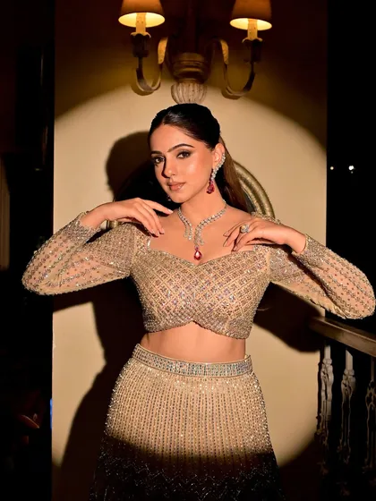 A dramatic shot capturing the full essence of this modern sangeet glam. The spotlight highlights the intricate details of her outfit and the radiant finish of the makeup.
