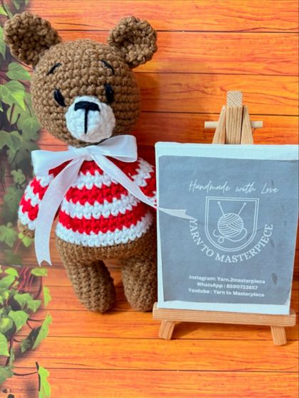 A festive teddy bear dressed in a red and white striped Christmas sweater, ready for the holidays.