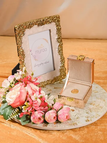 A gift that's both personal and elegant. This Rakhi hamper includes a stunning gold-textured photo frame and a small keepsake box, perfect for holding a special piece of jewelry or a coin.