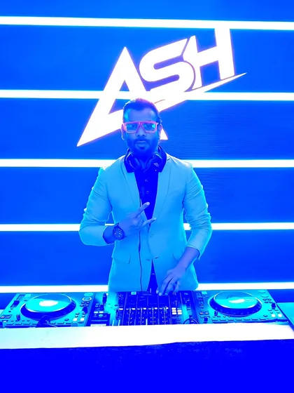Behind the decks with my logo lighting up the background. This is my office, where I blend genres and create the soundtrack for the night. It's not just about the volume, it's about the vibe.