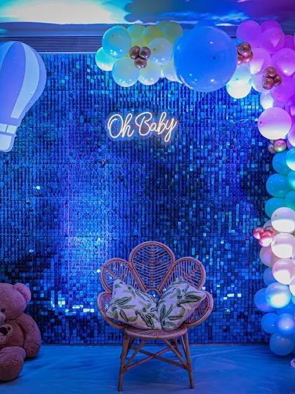 Modern, chic, and totally Instagrammable. This "Oh Baby" setup features a sparkling blue sequin wall, a trendy neon sign, and a gorgeous peacock chair, making the mom-to-be feel like a true queen on her special day.