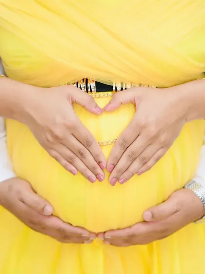 It's all about celebrating that beautiful bump. This close-up shot shows how our gowns are designed to lovingly frame your belly, making it the star of the show. The heart shape made by the parents' hands captures the love for their little one on the way.