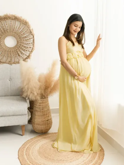 Gazing out the window, this portrait captures a quiet moment of reflection. The natural light beautifully highlights the mother's silhouette and the soft flow of her gown.