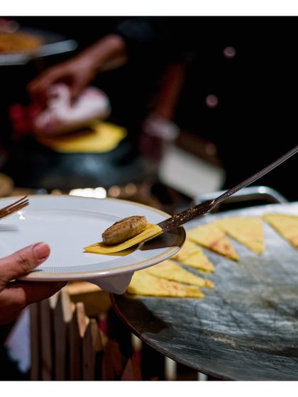 A freshly made gilauti kebab is carefully placed on a small, crisp bread base (bakarkhani). This close up shot emphasizes the delicate handling and perfect pairing of textures at our live tawa stations.