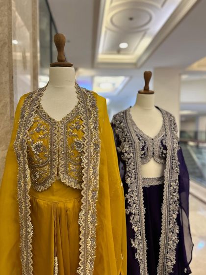 Another view of the jacket and lehenga sets, showcasing their flowing silhouettes and the shimmering silver embroidery.