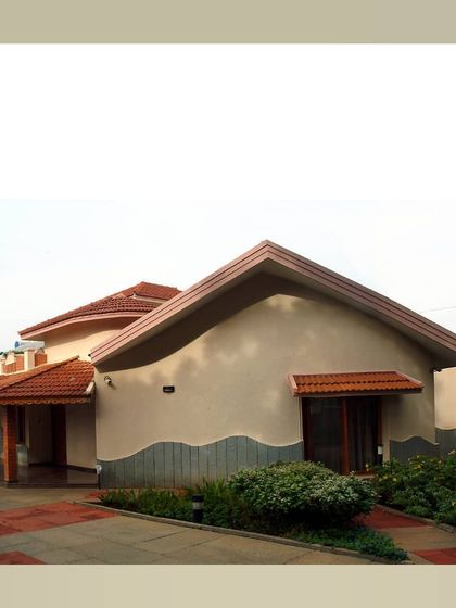 A home with a unique, flowing roofline and a lower wall of shaped stone, creating a sense of movement and connection to the earth.
