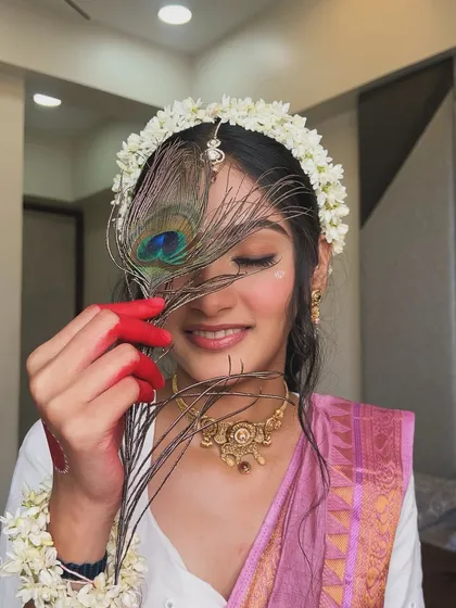 A playful and serene shot of the Radha look, with a peacock feather adding a touch of mystique. The makeup remains flawless, with a focus on the defined eyes.