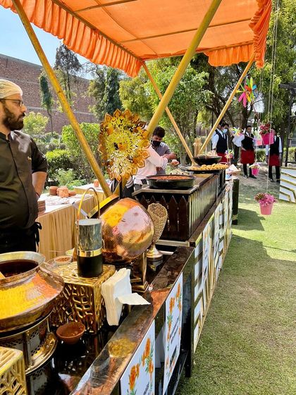 A beautiful outdoor live station for a Holi party. My chef is seen here preparing delicious food for guests amidst a colourful and festive setting.