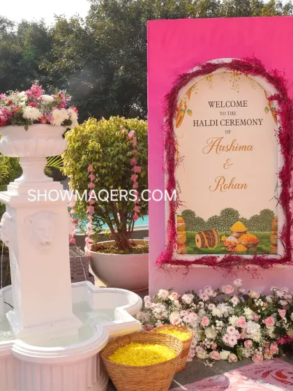 The welcome sign for Rohan and Ashima's Haldi ceremony, beautifully framed with pink florals and placed next to a classic white fountain.