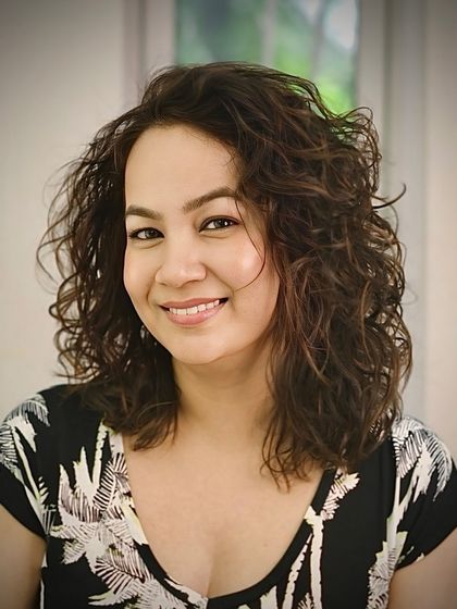 A happy client showing off her beautifully defined and healthy-looking curls after a session with our curl specialist.