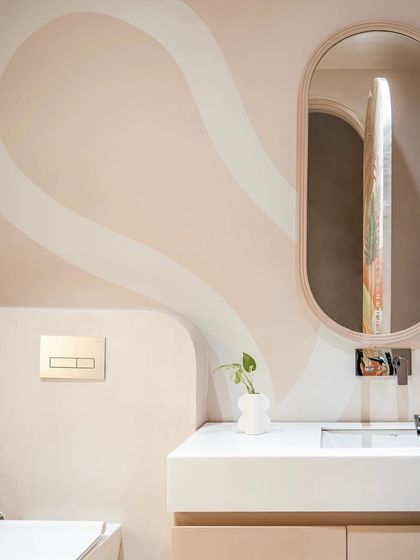 A close-up of the powder room's vanity. The oval mirror and gentle curves of the wall art create a soft, organic feel, turning a functional space into a small sanctuary.