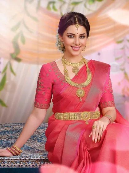 Another variation of the South Indian bridal look, this time with a rich pink saree. The styling focuses on the statement gold kamarbandh (waist belt) and matching necklace.