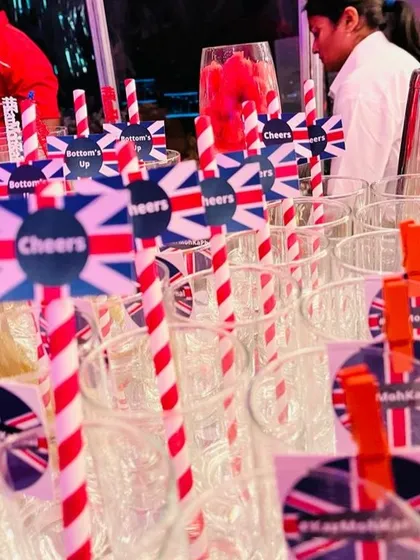 Every detail is on-theme, right down to the straws. Here, glasses are prepped with red-and-white striped straws and custom toppers featuring the Union Jack and celebratory messages like 'Cheers'.