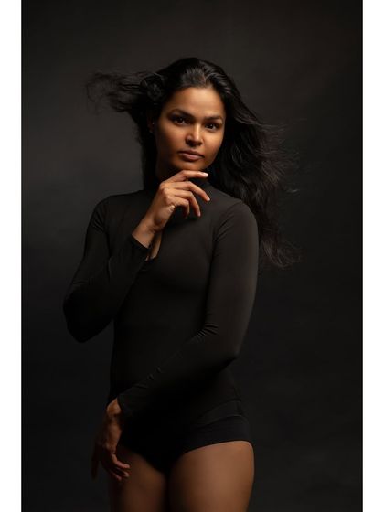 A powerful studio portrait with dramatic lighting. The wind-blown hair and strong pose create a sense of confidence and intensity.