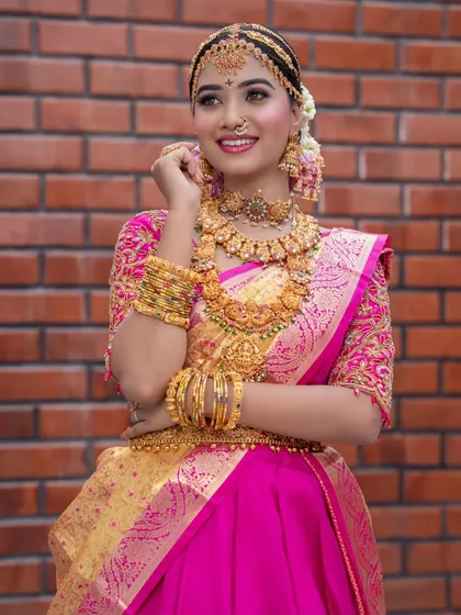 A three-quarter shot showing the rich embroidery on the blouse and the stunning temple jewellery.