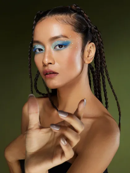 A dynamic shot that highlights the intricate details of the icy blue makeup and the model's confident pose.