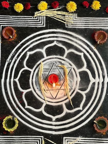 The yantra at the heart of the ritual, a geometric representation of divine energy. The lit diya symbolizes the awakening of our own inner light.