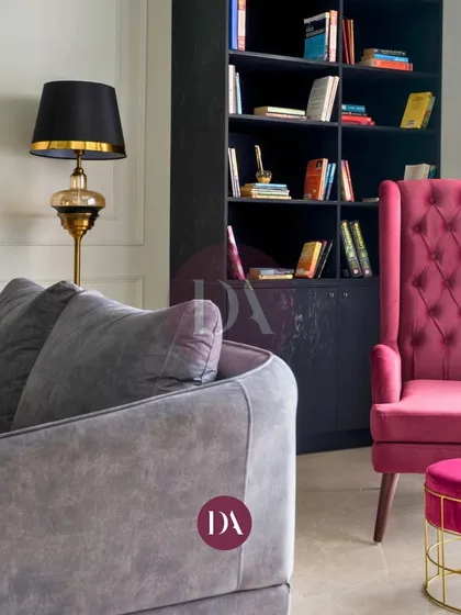 A detail shot showing the relationship between different seating elements in a living room. The grey sofa and magenta armchair create a dynamic color contrast, proving that thoughtful furniture selection is key to a cohesive design.