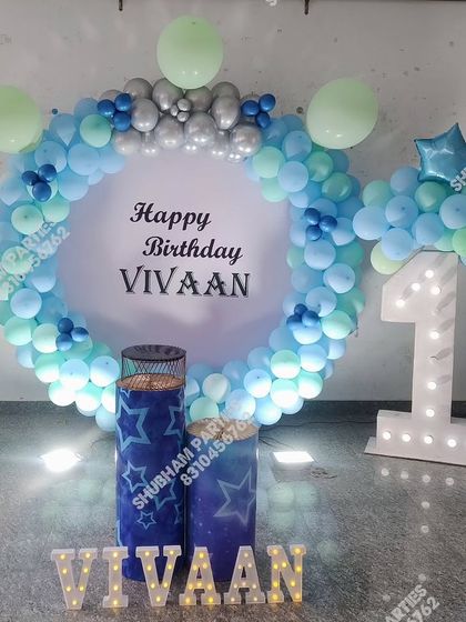 A blue and white themed first birthday setup with a large balloon ring and a light-up number one.