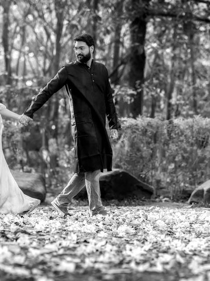 A romantic black and white photo of the couple walking hand-in-hand. The monochrome treatment gives the scene a timeless, storybook quality.